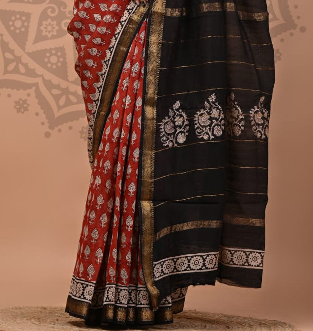 Woman wearing a red and black saree with white patterns on a beige background