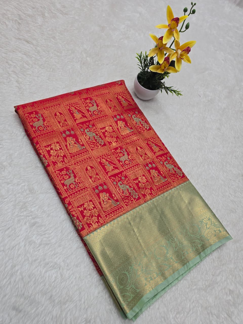 Red and green traditional saree with a plant on a light gray background