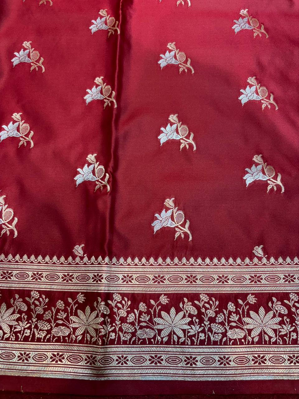 Red fabric with white floral patterns and intricate border
