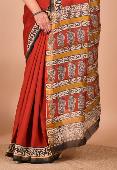 Woman wearing a red saree with intricate patterns on a beige background