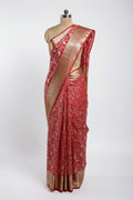 Red saree with white floral patterns and gold border on a green surface