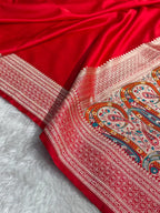Red fabric with intricate white and multicolor patterns on a white background