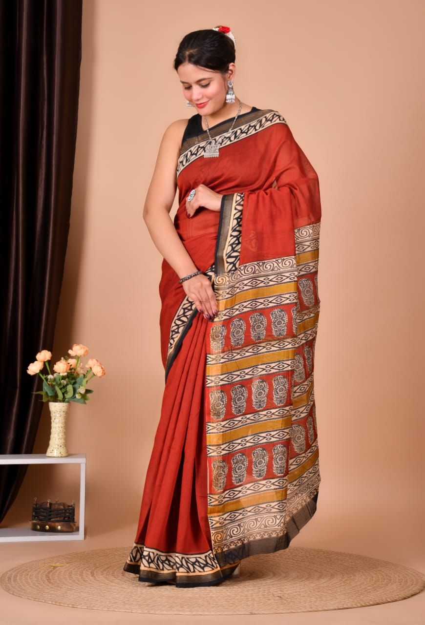 Woman wearing a red saree with intricate patterns on a beige background