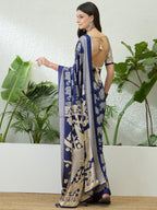Woman wearing a blue and white saree with a plant background