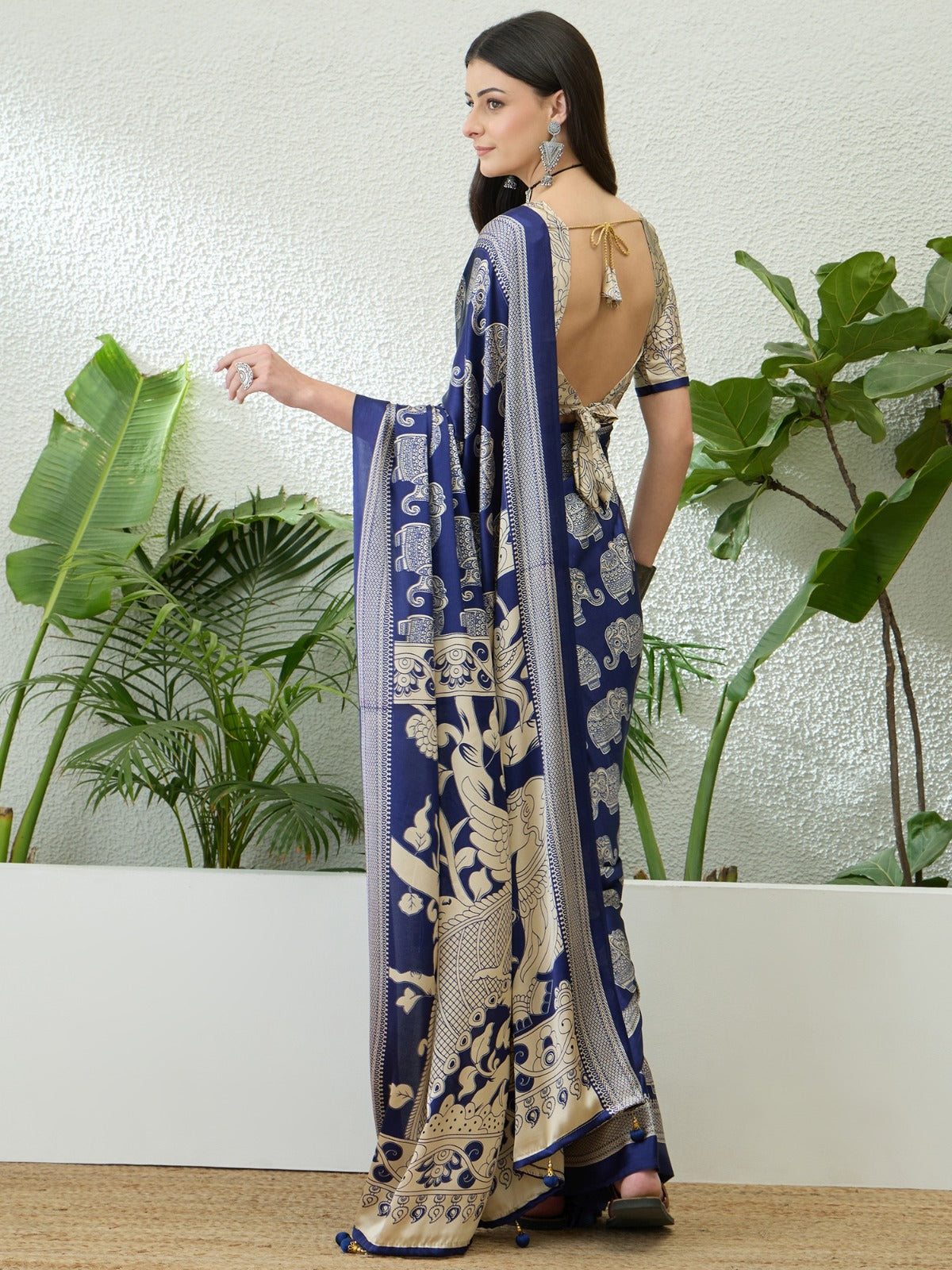 Woman wearing a blue and white saree with a plant background