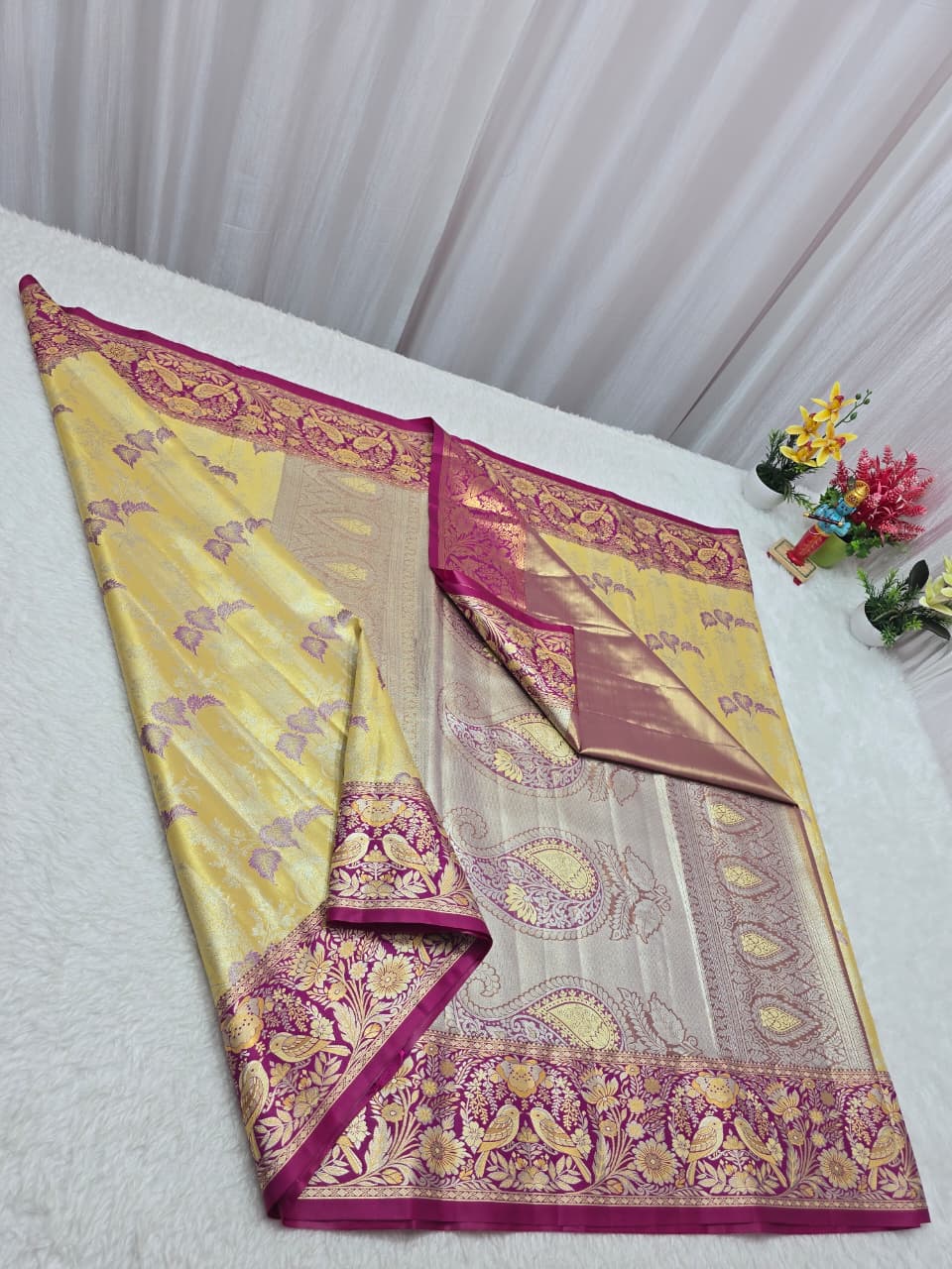 Yellow and white saree with pink border on a white surface