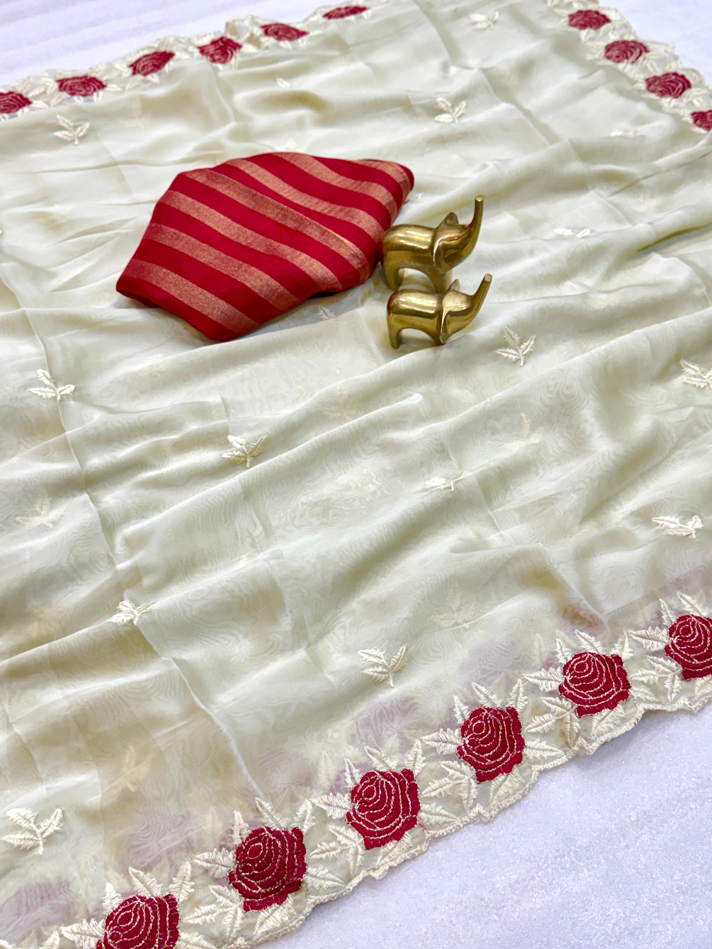 White saree with red floral patterns and a red and gold blouse on a white background