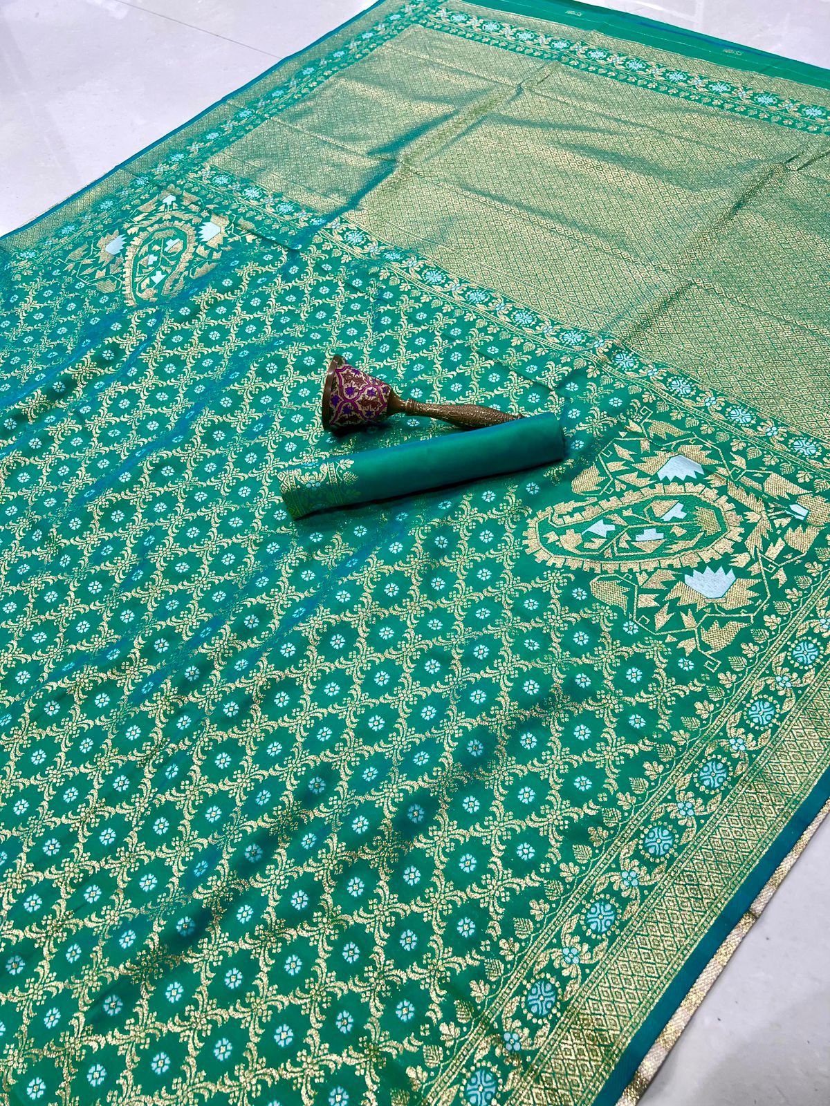 Green patterned fabric with a decorative brooch on a white background