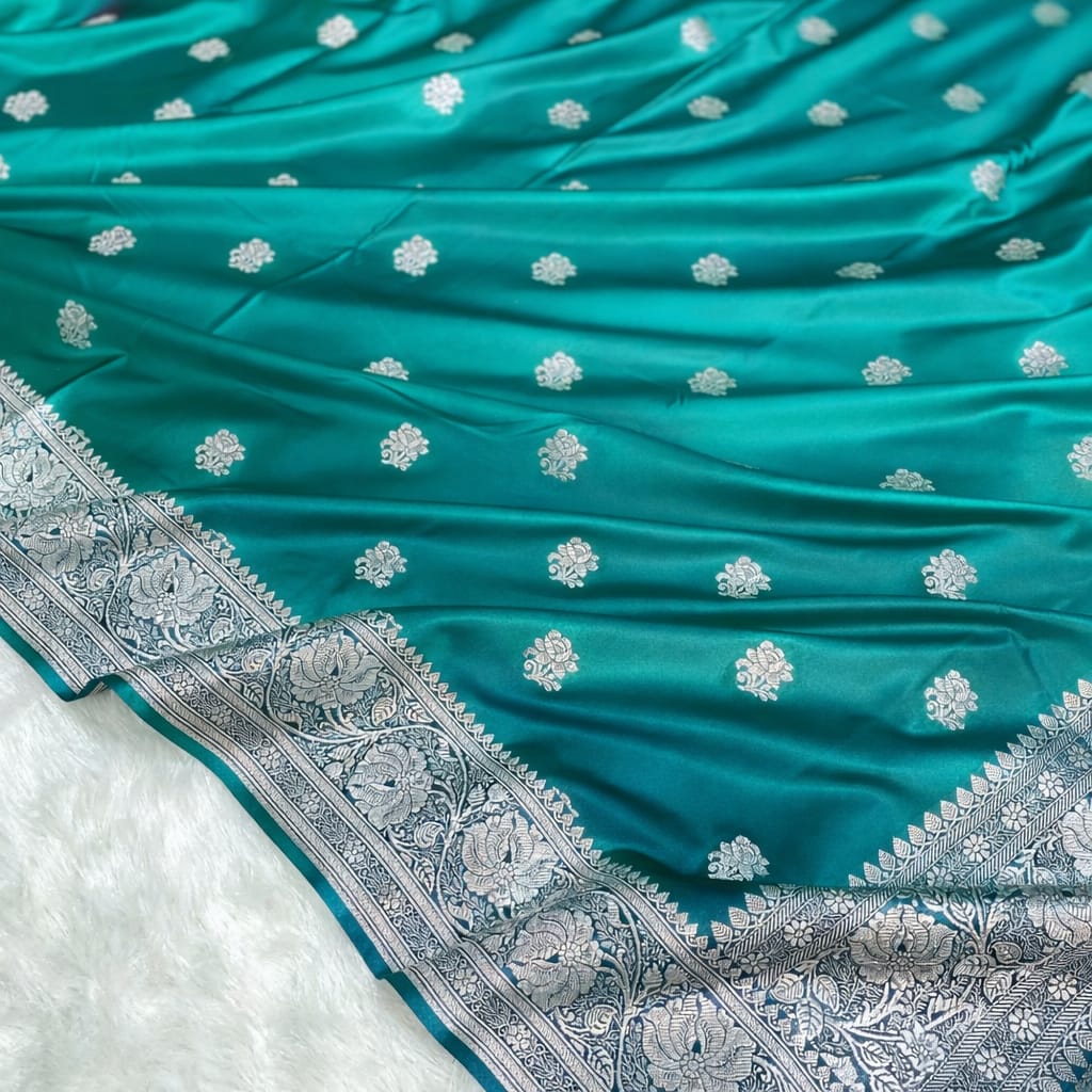 Teal fabric with white floral patterns and intricate silver border on a white background