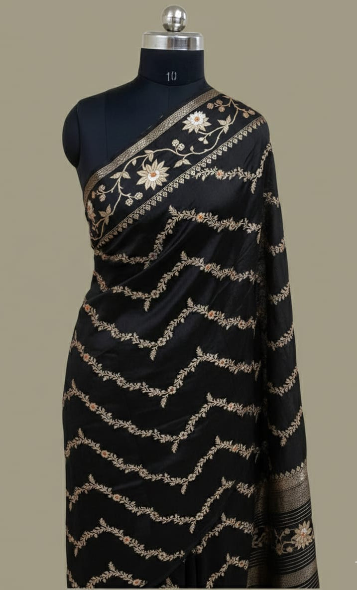 Black saree with gold embroidery on a mannequin against a gray background