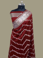 Red saree with white patterns on a mannequin against a beige background