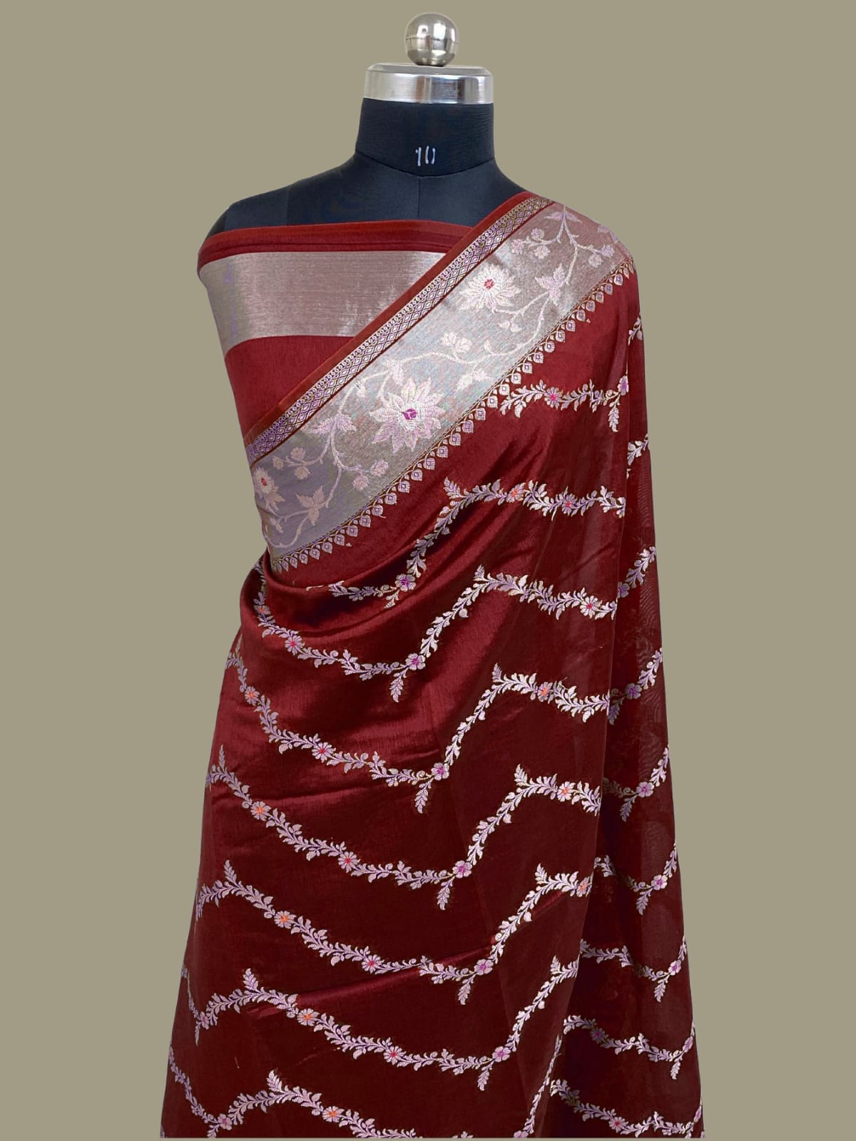 Red saree with white patterns on a mannequin against a beige background