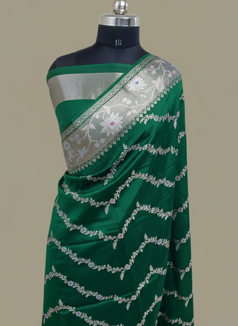 Green saree with silver border on a mannequin against a beige background