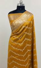 Yellow saree with white lace on a mannequin against a light gray background