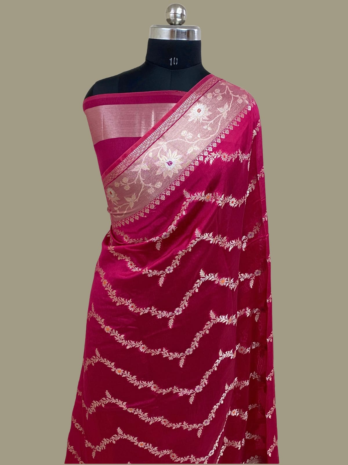 Pink saree with white embroidery on a mannequin against a beige background