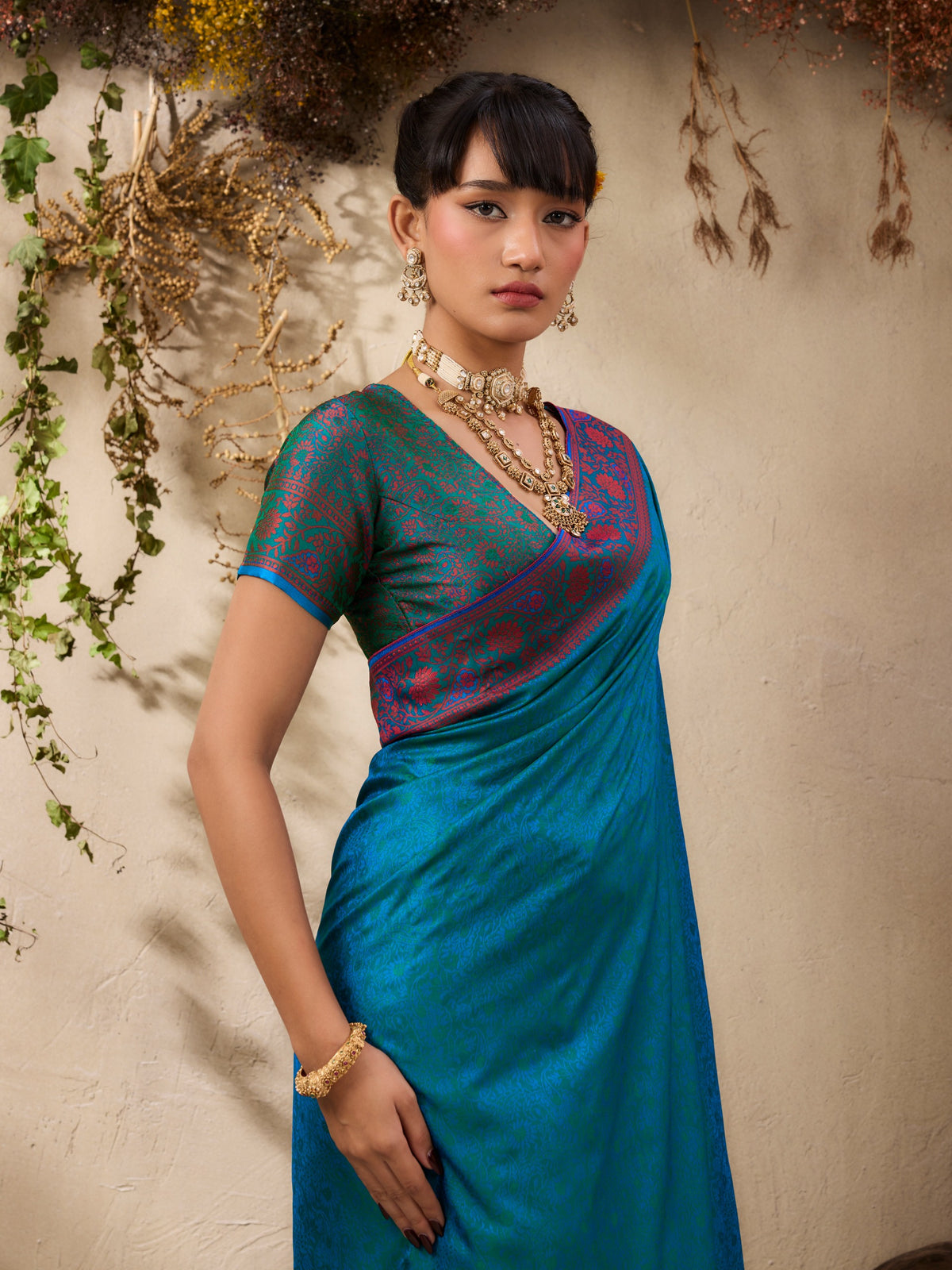 Woman wearing a blue saree with a patterned blouse against a neutral background