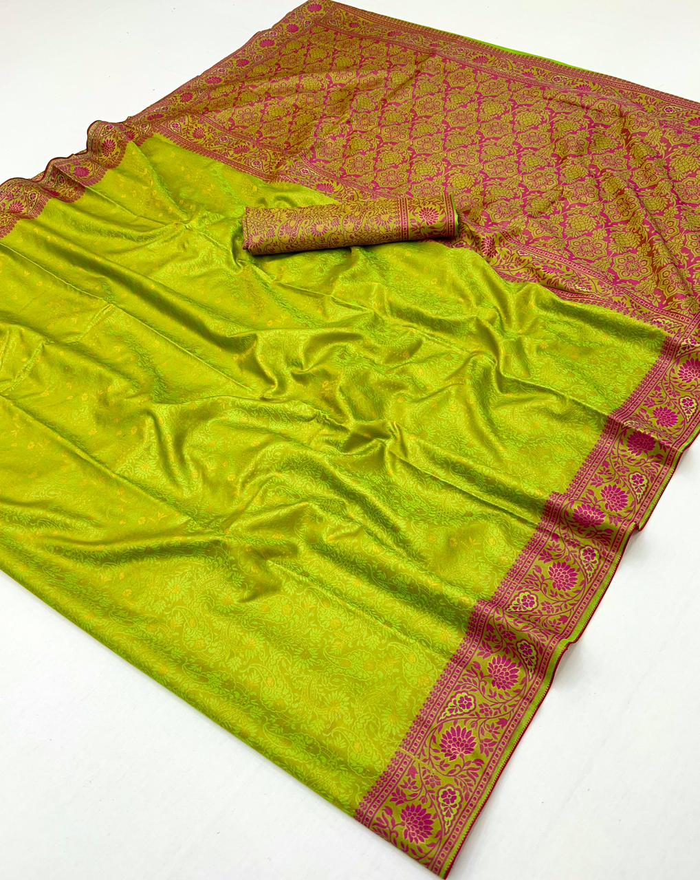 A lime green silk saree with a pink and gold woven border and matching inner roll, displayed on a white background.