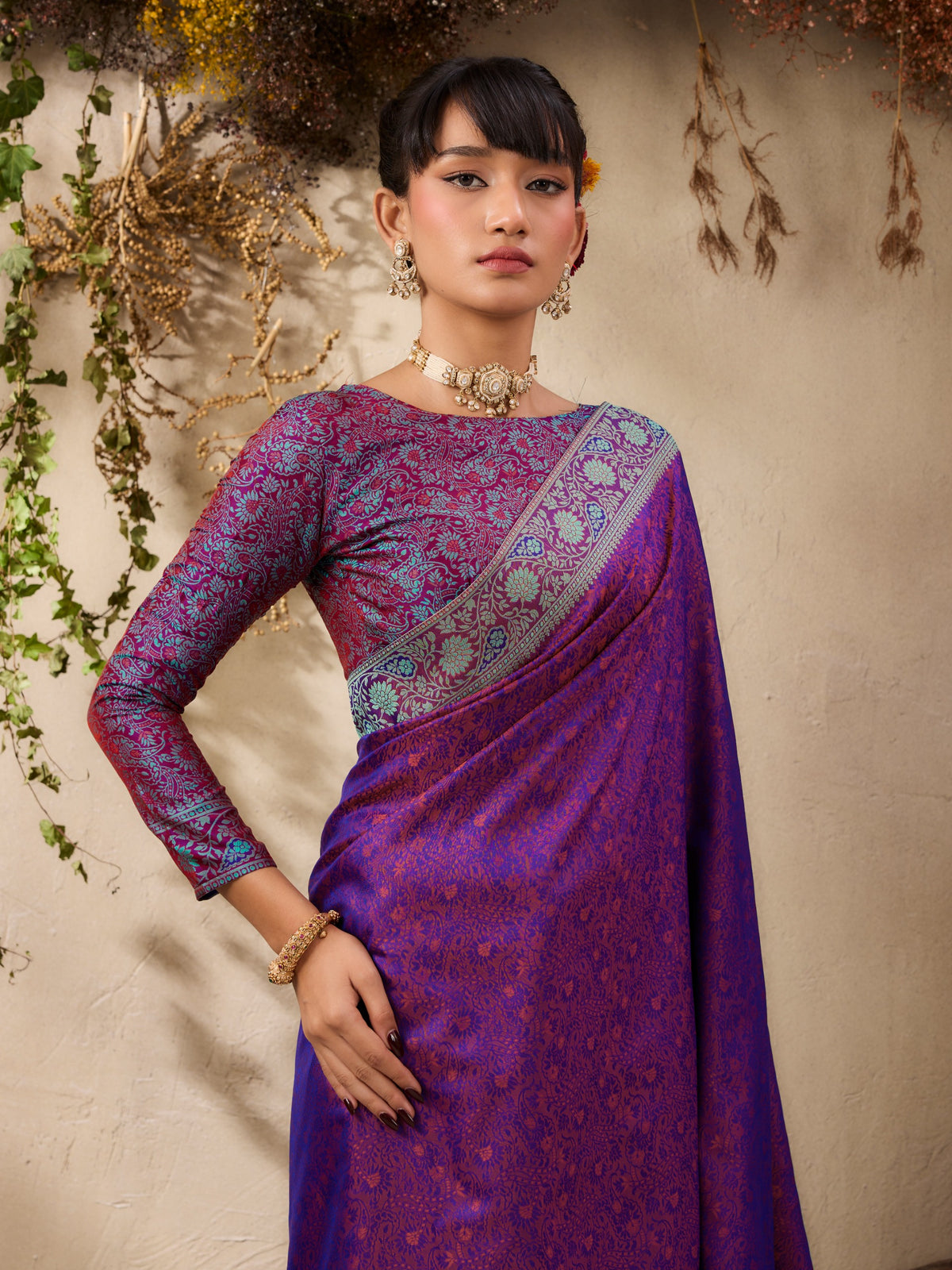 Woman wearing a purple saree with a textured pattern against a neutral background