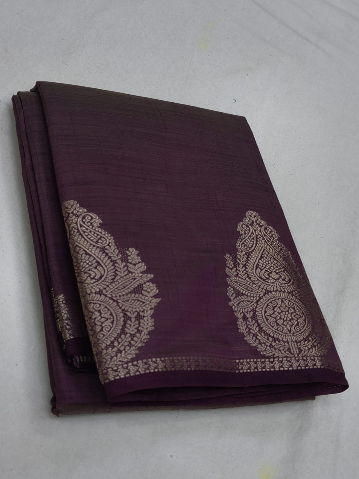Folded purple fabric with silver embroidery on a white background