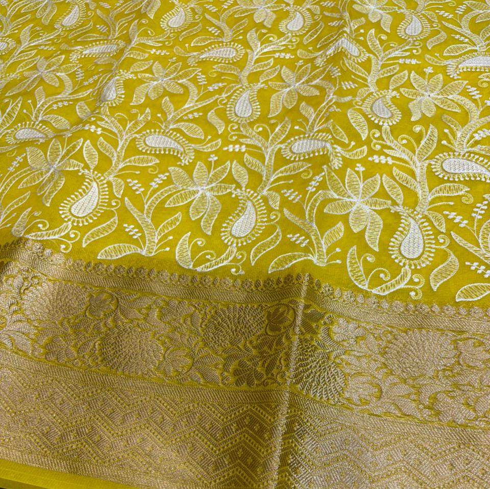 Yellow fabric with intricate white floral patterns on a dark surface