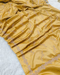 Mustard yellow fabric with intricate gold embroidery on a white background