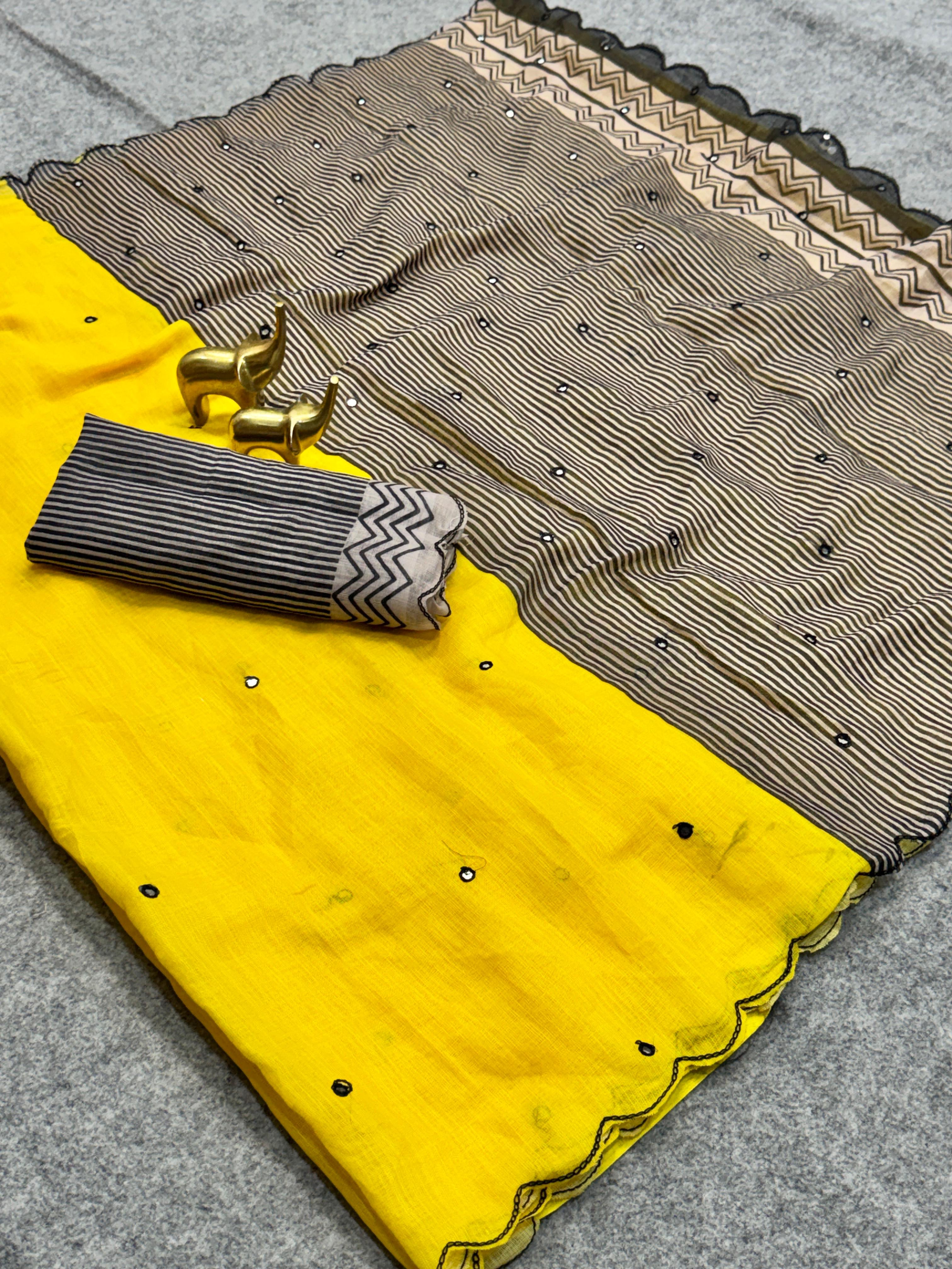 Yellow fabric with a patterned border and decorative elements on a gray surface