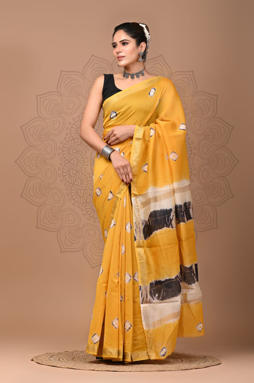 Woman wearing a yellow saree with black and white patterns on a beige background