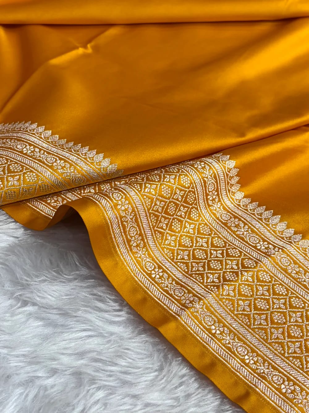 Orange fabric with intricate white patterns on a fluffy white surface