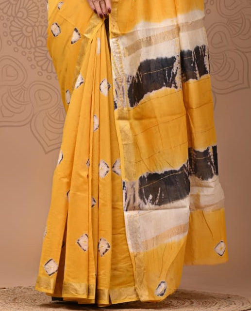 Woman wearing a yellow saree with black and white patterns on a beige background