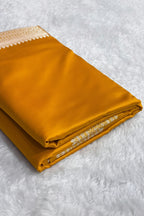 Folded mustard yellow fabric with a pattern on a white surface, Zara box visible.